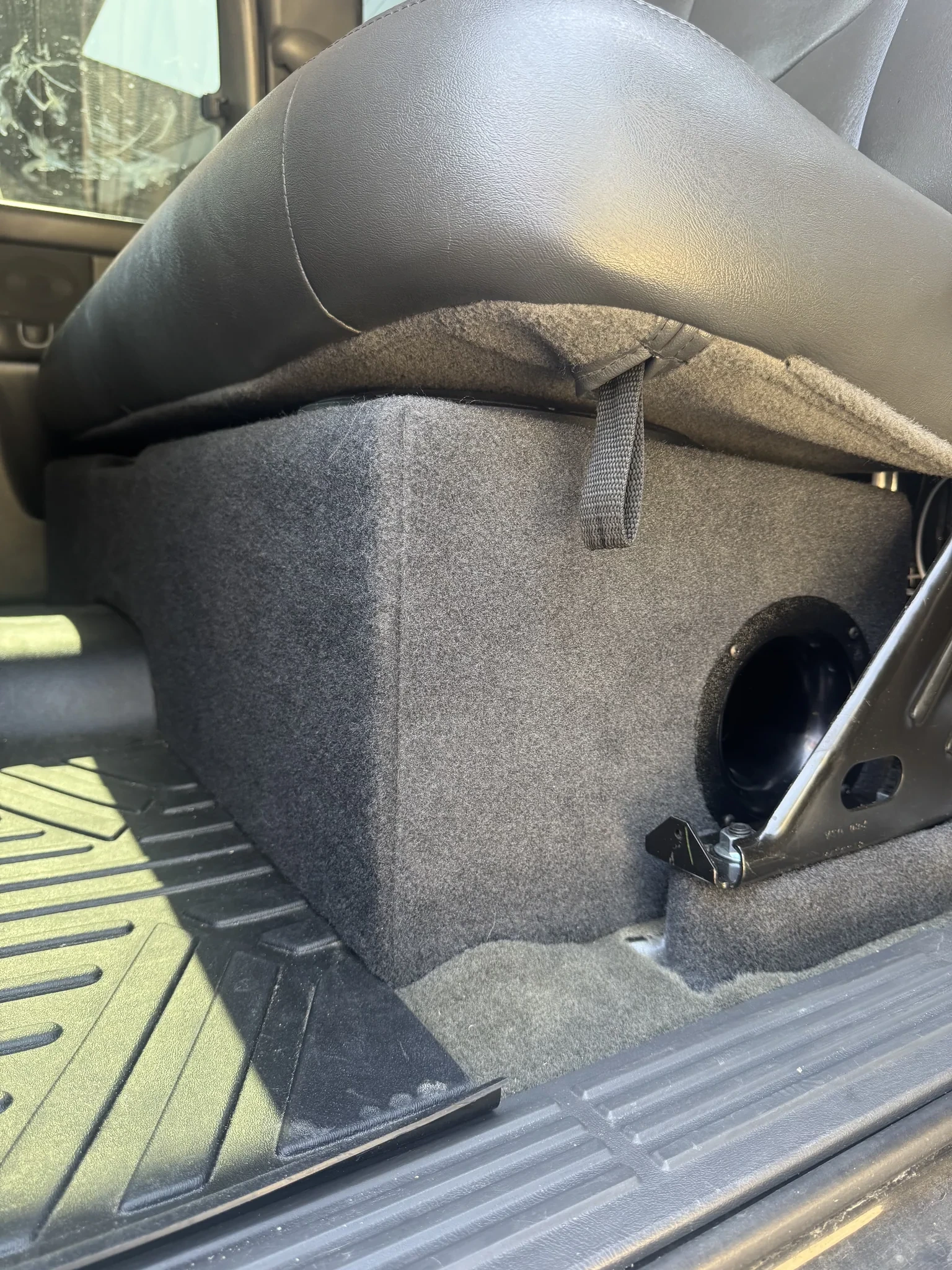 Finished carpeted under-seat subwoofer enclosure in a Silverado extended cab with the rear seat down