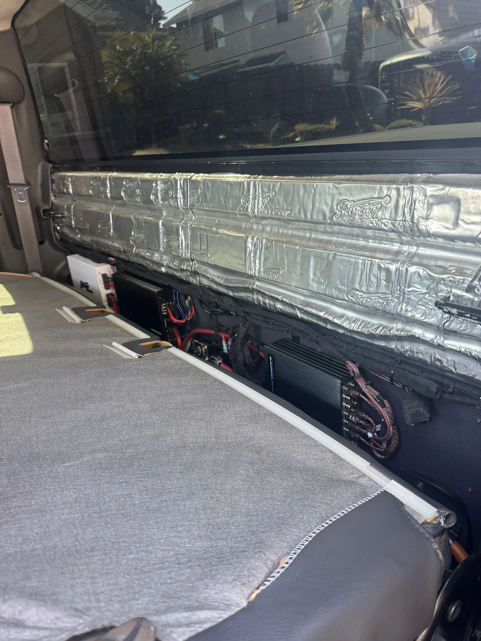 Amplifier rack mounted on the rear cab wall of a Silverado with Zapco, AudioControl and Stinger amplifiers