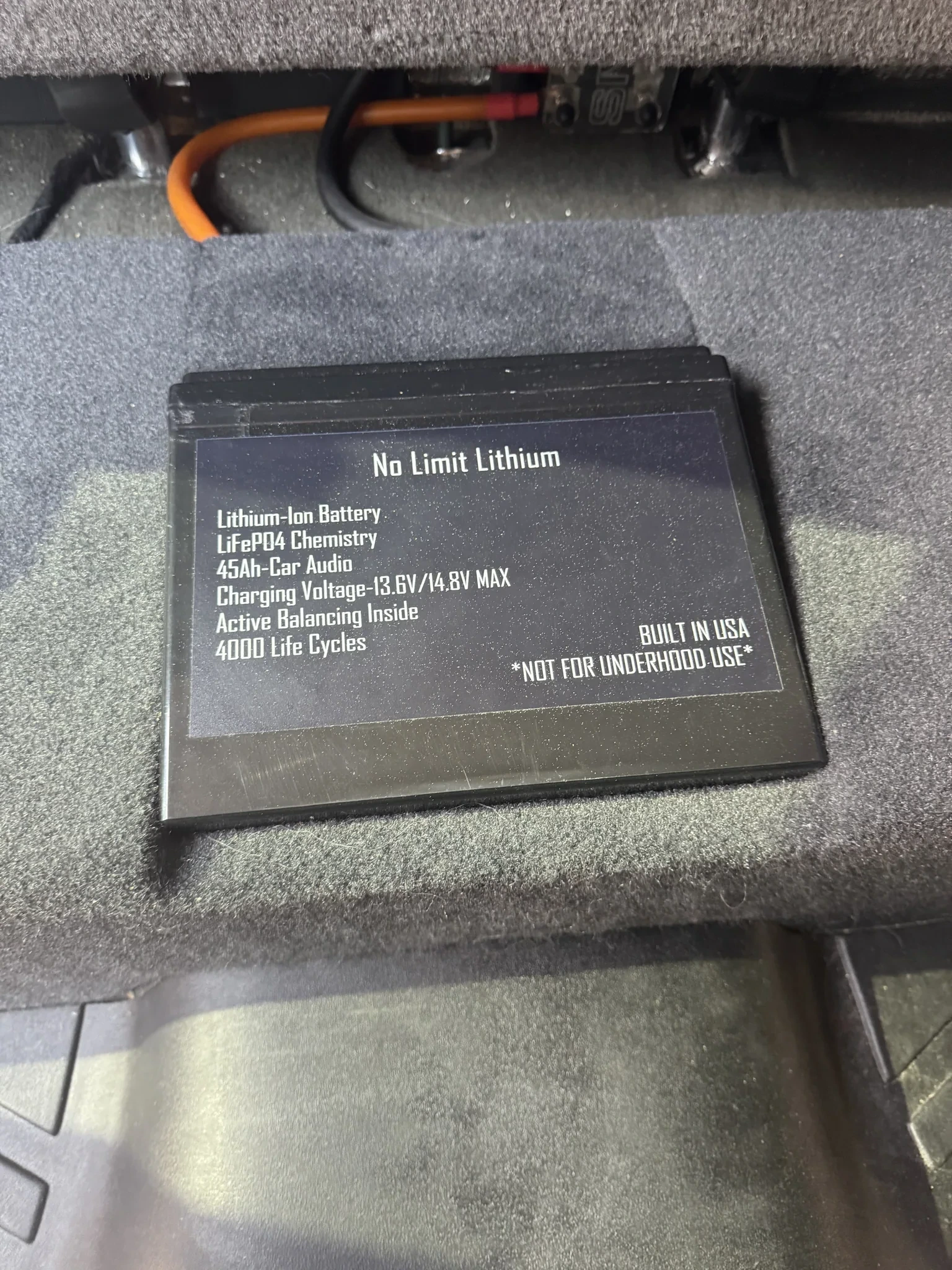No Limit Lithium 45Ah LiFePO4 battery mounted on top of a carpeted subwoofer enclosure