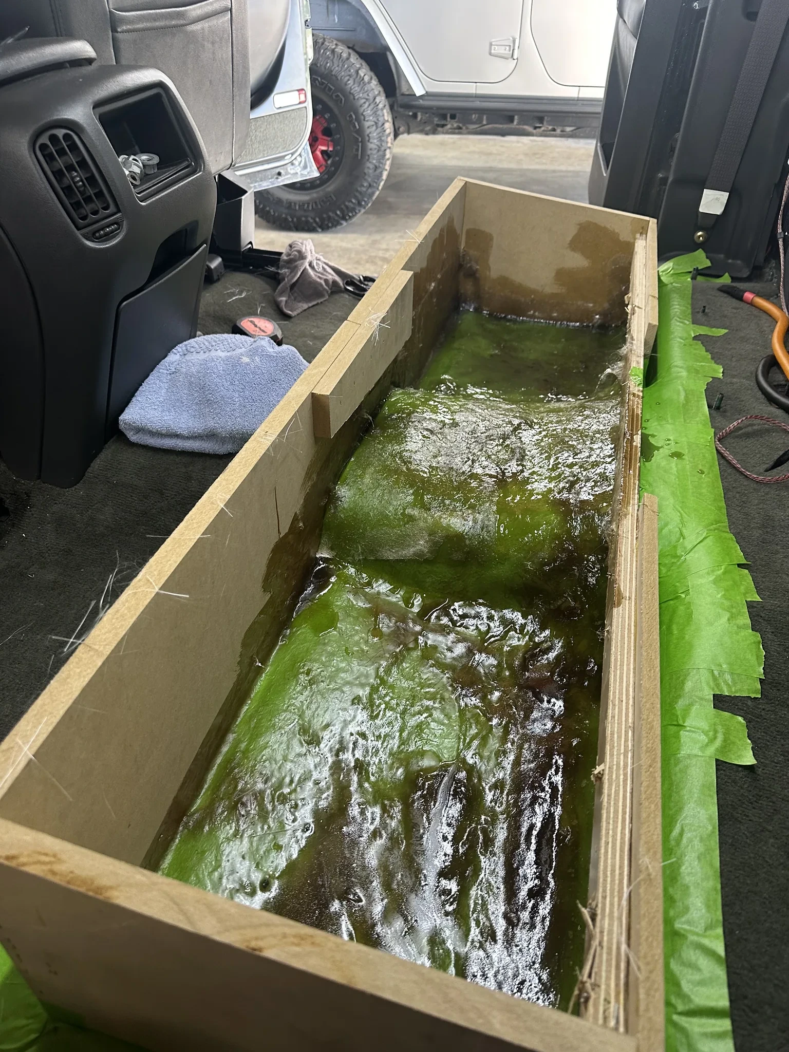 Fiberglass and resin being laid into an MDF enclosure frame inside a Silverado cab
