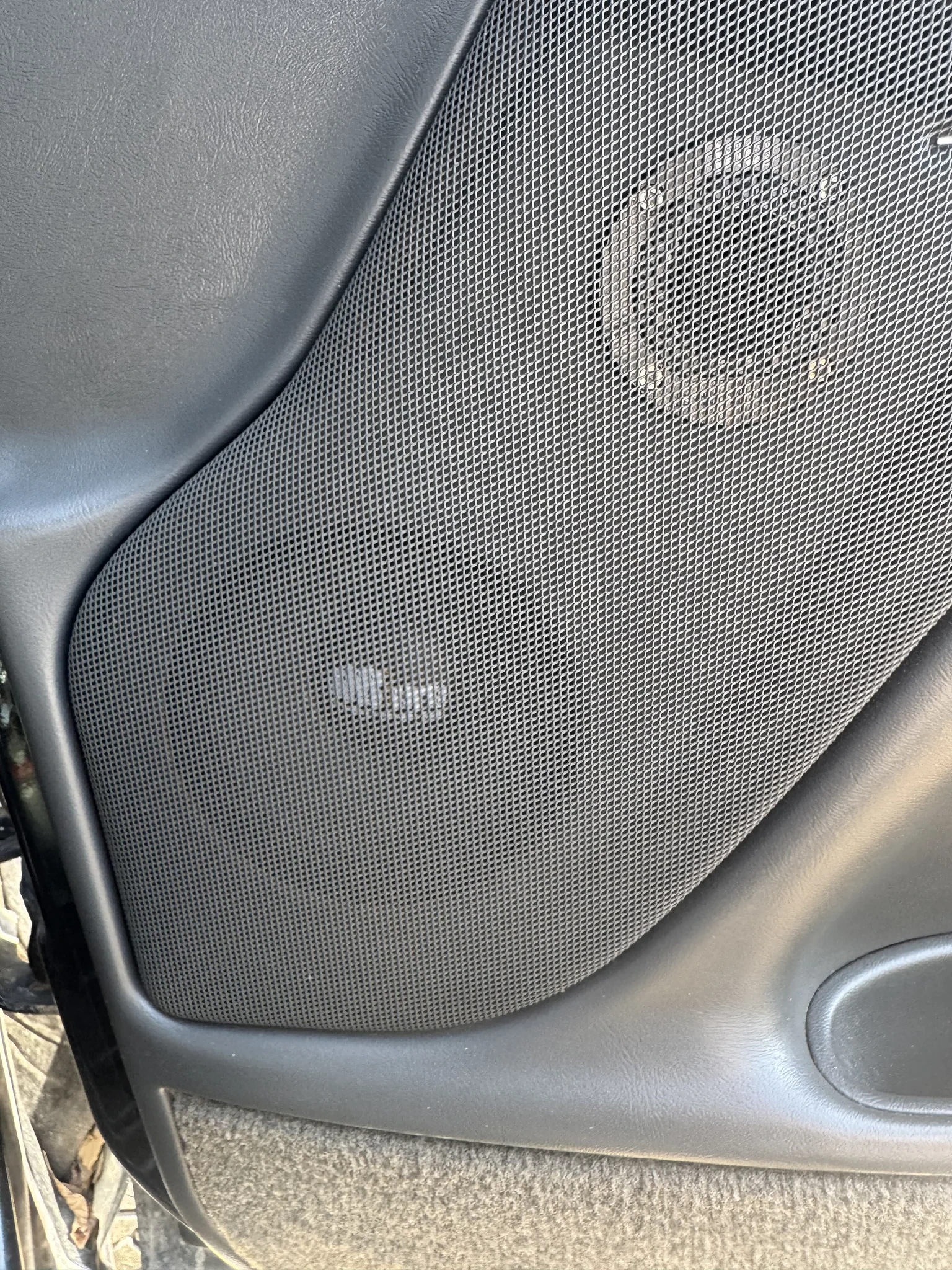 Factory door speaker grille in a 2004 Silverado with aftermarket drivers installed behind it