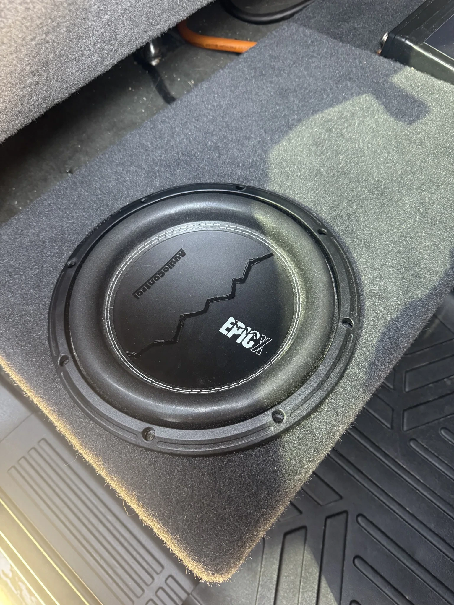 AudioControl EPIC X 10-inch subwoofer mounted up-firing in a carpeted under-seat enclosure